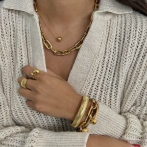 A woman wearing gold jewelry and a white sweater.