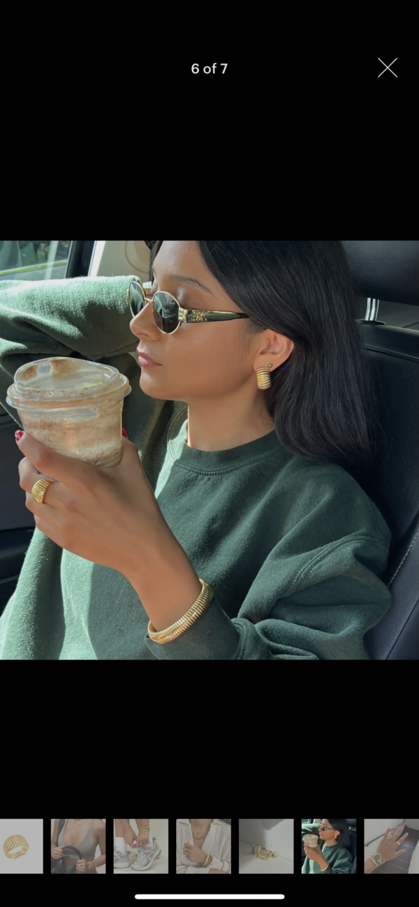 A woman sitting in the back of a car drinking coffee.