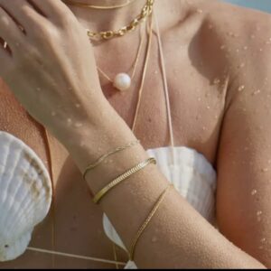 A woman wearing jewelry and a white bikini top.