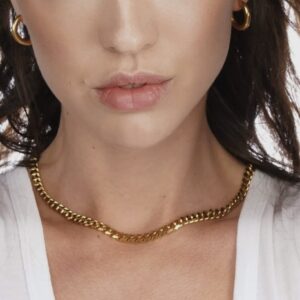 A woman wearing a gold chain necklace and earrings.