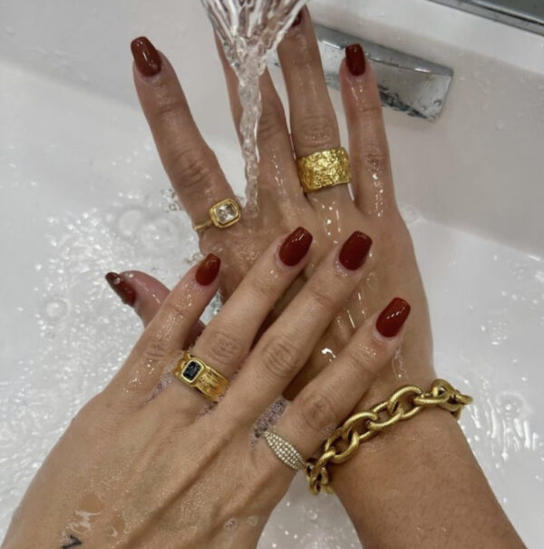 A woman with red nails and gold jewelry.