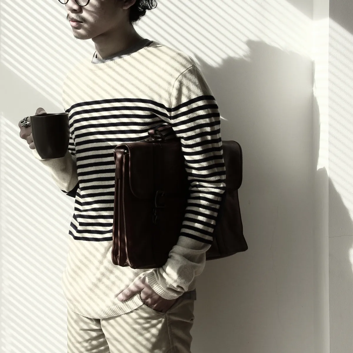 A man in striped shirt holding a bag.