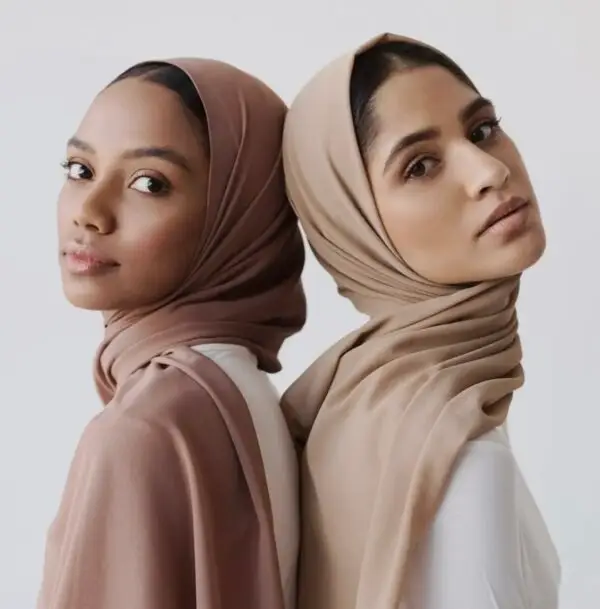 Two women in a tan and brown hijab pose for the camera.