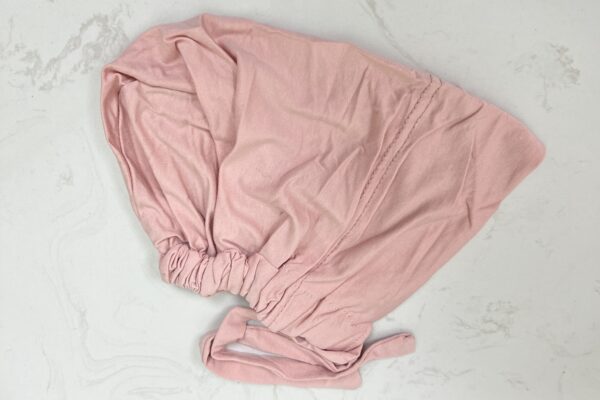 A pink sheet sitting on top of a bed.