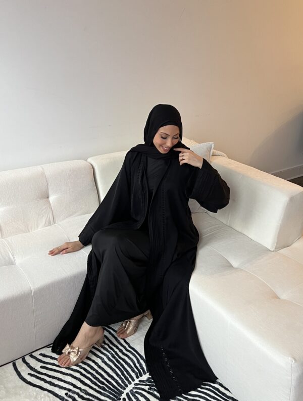 A woman in black robe sitting on white couch.